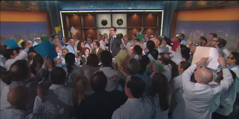Fotograma del programa de Last Week Tonight. Se ve a 97 científicos mostrando informes y pruebas a tres negacionistas del cambio climático. John Oliver, el presentador, trata de poner orden en el caos.